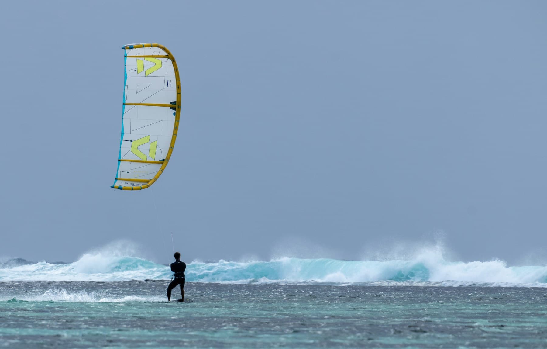 Kitesurfer riding in rough turquoise waves in Mauritius