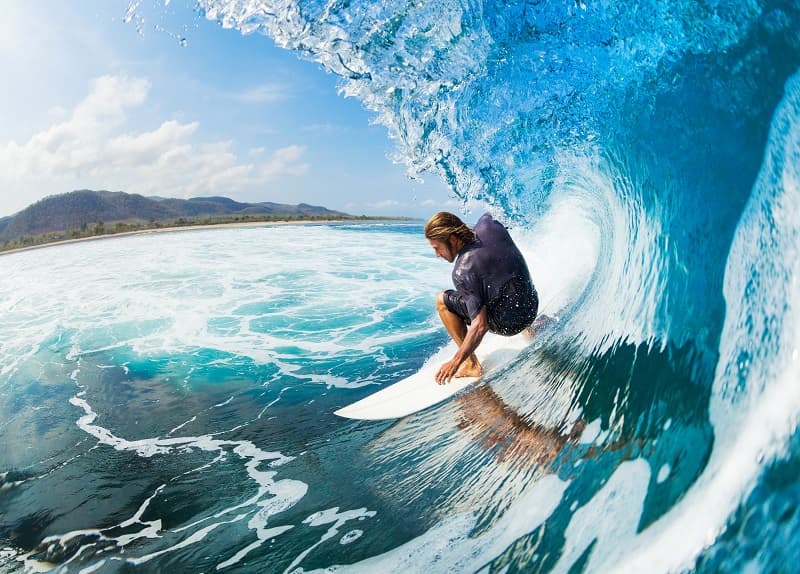 Experienced surfer riding inside a turquoise reef wave near Le Morne